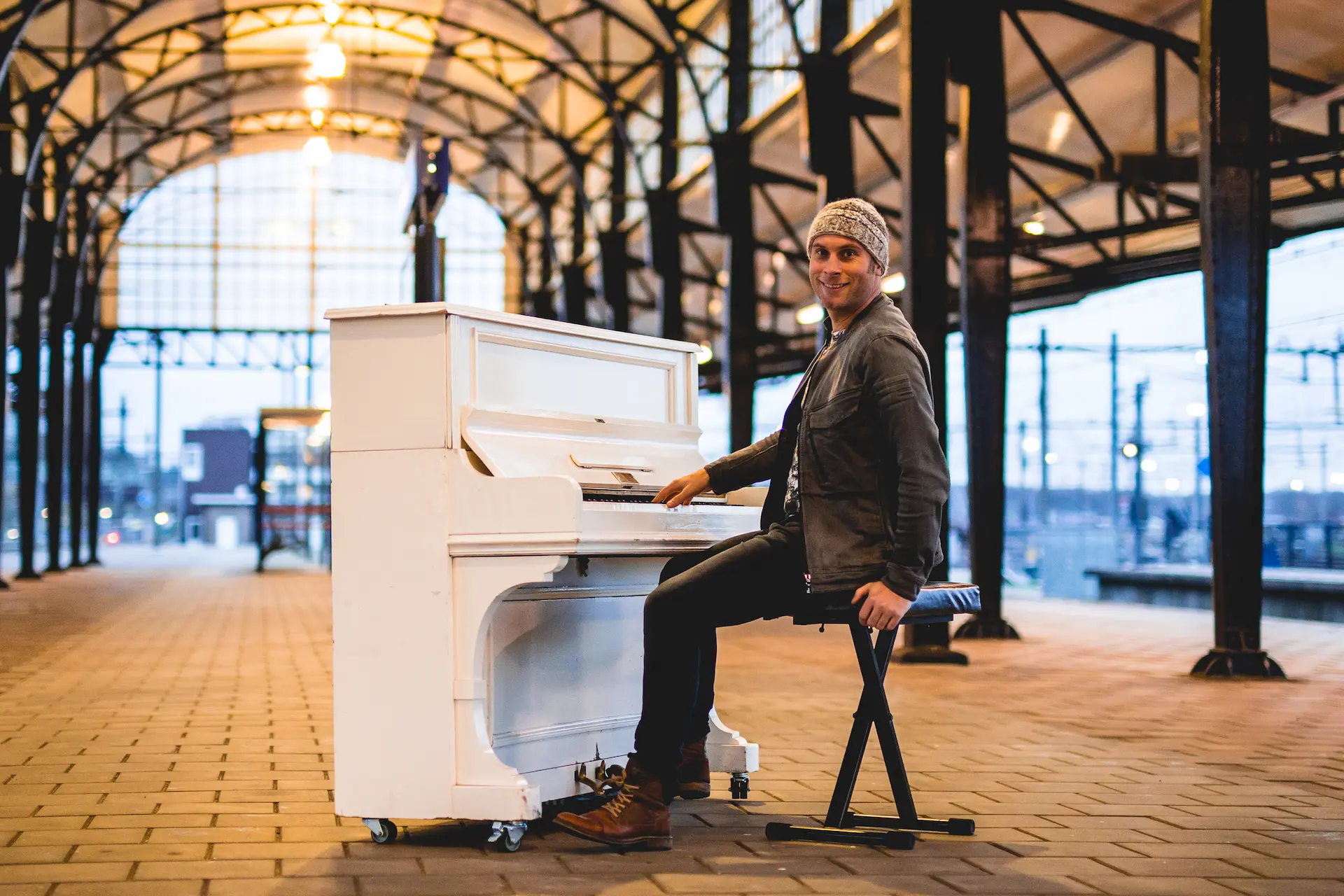 Zanger en pianist Jelle, De Pianoman, speelt live muziek op een witte piano in een sfeervolle setting.
